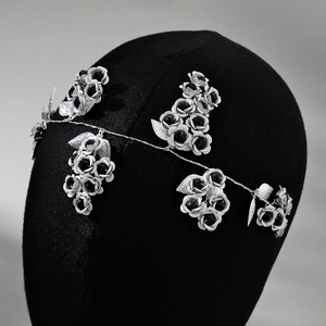 Close-up of handmade bridal headband with black and white metallic roses and silver leaves