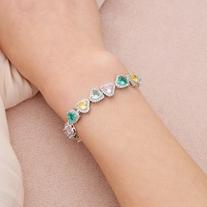 Détail de pierres précieuses en cœur sur un bracelet argenté avec bordures en zircons