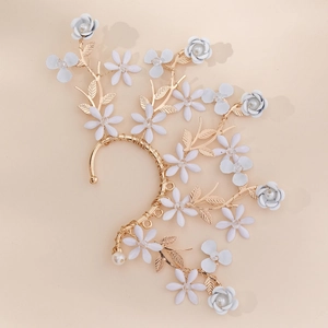 Détail d'un ear cuff floral avec fils dorés, fleurs blanches et perles pour les mariages
