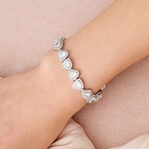 Gros plan d'un bracelet en zircon en forme de cœur avec serti halo sur le poignet