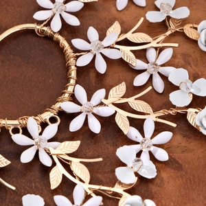 Élégant contour d'oreille doré avec fleurs blanches et perles sur fond bois rustique