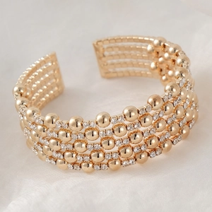 Detail of multi-layered gold cuff bracelet featuring polished beads and sparkling crystals