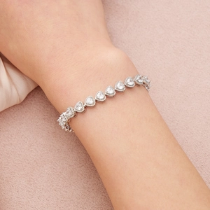 Gros plan d'un bracelet argenté avec zircons cubiques en forme de cœur au poignet