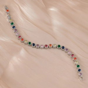 Vue rapprochée d'un bracelet cœur arc-en-ciel coloré sur un tissu de soie champagne chic