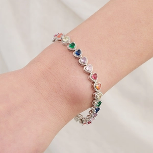 Détail d'un bracelet de zircones multicolores en forme de cœur sur un poignet féminin