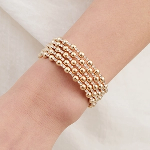 Detail of five-layer gold bracelet with stacked beads and micro-set zircon on model wrist
