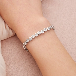 Vue détaillée du bracelet avec zircons en forme de cœur sur fond de tissu rose élégant