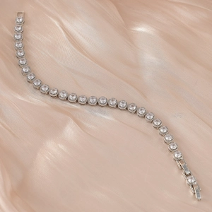 Gros plan du bracelet tennis en argent avec zircons sur un tissu en soie champagne