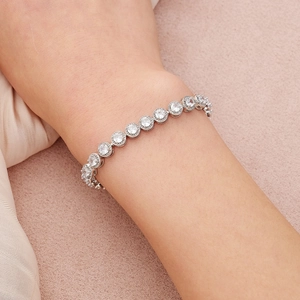 Gros plan d'un bracelet tennis argenté avec oxydes de zirconium sur tissu en soie rose