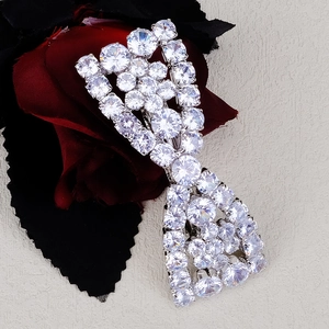 Macro shot of sparkling zircon flower hair clip with silver finish on dark floral backdrop