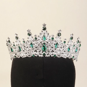 Vue détaillée de la couronne argentée avec cristaux verts sur support en velours noir
