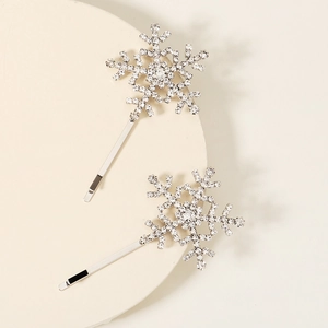 Detail shot of two silver snowflake hair pins with sparkling white rhinestones on a plate