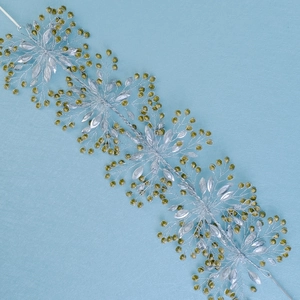 Detailed view of silver woven bridal headband with green crystals and rhinestones