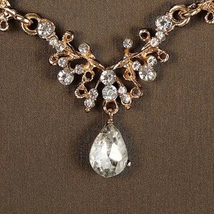 Détail du collier couronne dorée avec pendentif en cristal en goutte et pierres de zircon rondes