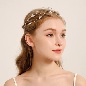 Dettaglio fascia da sposa con delicati fiori bianchi e perle su filo d'oro intrecciato