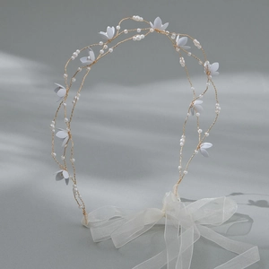 Dettaglio della fascia da sposa fatta a mano con fiori bianchi, perle e nastri d'organza