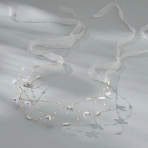 Dettaglio fascia da sposa con fiori bianchi, perle e nastro in organza traslucido