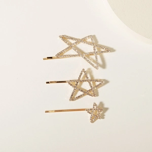 Detailed view of three gold star-shaped hairpins with sparkling inlaid rhinestones