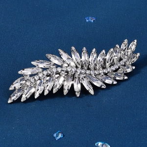 Elegant silver leaf hair clip with marquise cut rhinestones on a textured blue surface