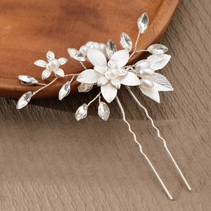 Close-up of handmade bridal hair pin with pearls and crystals in leaf and floral design