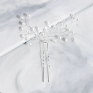 Detail view of handcrafted pearl hair pin with silver branch wires on marble background