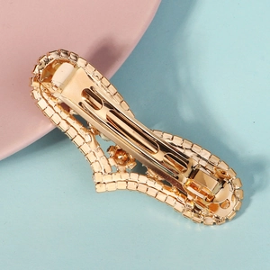Barrette à cheveux dorée avec cœur et lettres XOXO sertie de strass sur fond doux