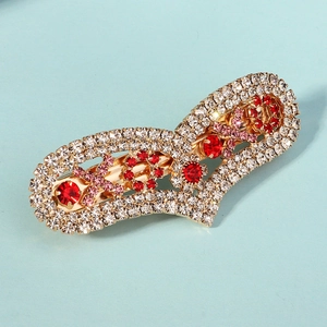 Détail d'une pince à cheveux dorée ornée de cristaux rouges et roses à motifs floraux