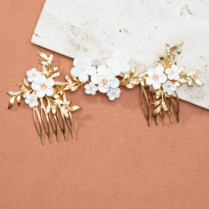 Macro detail of bridal hair comb with gold leaves, white clay flowers and sparkling crystals