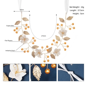 Detail view of bridal gold leaf headband with clay flowers and imitation pearls on blue fabric