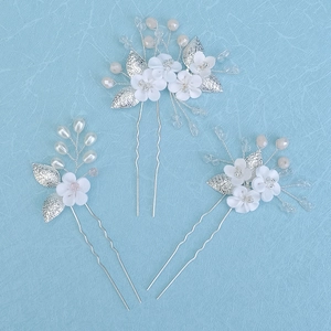 Detailed close-up of handmade bridal hair pins with white clay flowers and pearls