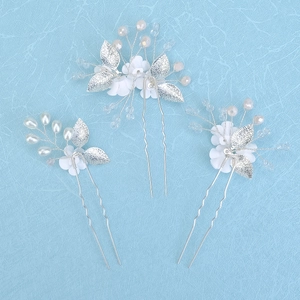 Detailed close-up of handmade bridal hair pins with white clay flowers and pearls