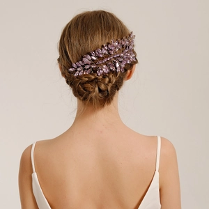 Detailed back view of a bride with a purple crystal leaf hairpiece in a braided updo