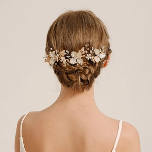 Détail d'un peigne à cheveux de mariée avec fleurs dorées et perles sur chignon élégant