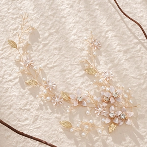 Close-up of bridal headband with handmade pink fabric flowers and golden leaf details