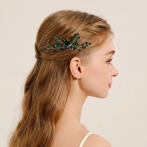 Detail of silver leaf hair comb with emerald green crystals on braided hair