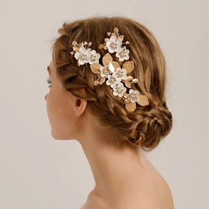 Détail des épingles à cheveux à feuilles dorées et fleurs blanches sur une mariée