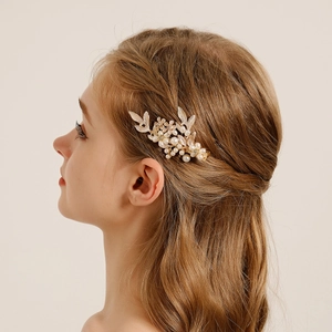 Detailed close-up of a bridal leaf hair clip with pearls worn on the side of the hair