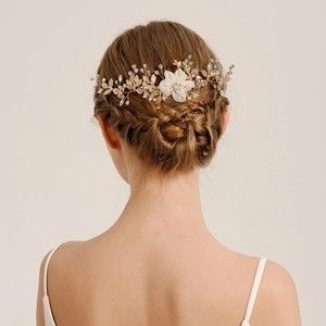 Close-up of bridal hair comb with white fabric flowers and sparkling crystals on hairstyle