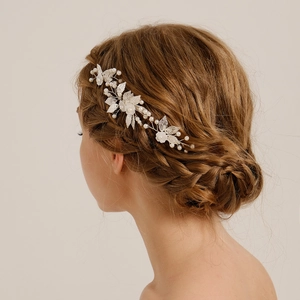 Eleganter Braut-Haarkamm mit silbernen Blättern, weißen Blumen und Perlen am Modell