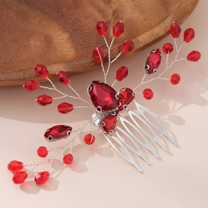 Detailed close-up of handmade bridal hair comb with red crystals and silver metal branches