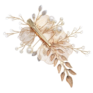 Macro shot of gold wire petals and pearls on the back of a vintage bridal hair clip