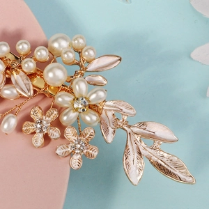 Close-up of golden floral hair clip with pearls and sparkling rhinestones for bridal hairstyle