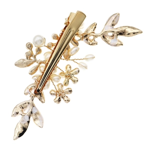 Detail of handcrafted gold alloy hair clip with white pearls and leaf motifs for brides