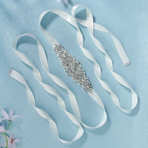 Close-up of bridal belt featuring luxury hand-sewn rhinestones and pearls on white satin