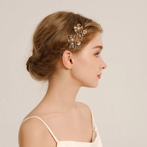 Macro detail of bridal gold flower hair comb with white pearls on a model's hair