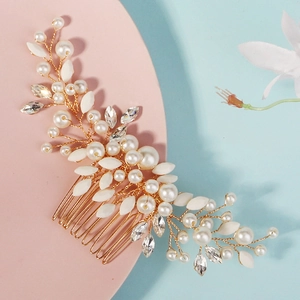 Détail d'un peigne de mariée avec perles, cristaux et feuilles d'or sur fond pastel