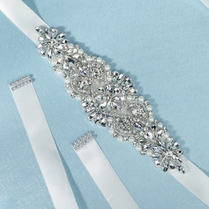 Close-up of sparkling rhinestones and pearls on a white bridal satin sash belt