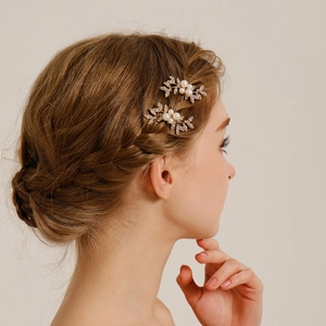 Detailed close-up of pearl and crystal leaf bridal hair pins on gold alloy base
