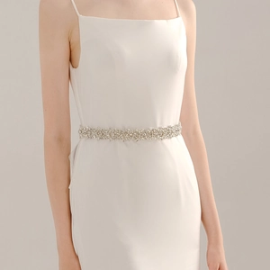 Elegante cintura da sposa con strass scintillanti e cristalli floreali su un abito bianco