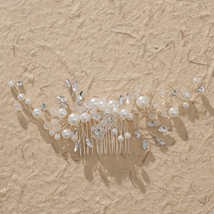 Détail d'un peigne de mariée avec perles et strass marquise sur fond en papier texturé